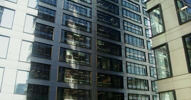 High-rise office building with large stained-glass windows. Business center of the modern city. Light in the windows of office workers. in 4k, red komodo video