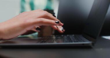 fechar-se tiro do mão do jovem europeu mulher digitando em computador portátil teclado enquanto sentado às mesa dentro escritório, trabalhando em diagrama video