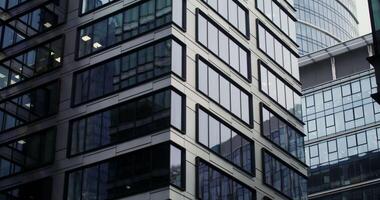 Facade of modern office buildings with large panoramic windows. Semicircular glass skyscraper in the business center of the city. Dynamic shooting from the bottom up. in 4k, red komodo video