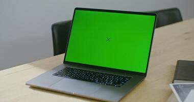 An open laptop with a green screen stands on the architect's desktop, next to the blueprints, copy space, chroma key, no people in the video