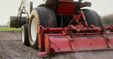 Close-up of a tractor with a plow plowing a field on an autumn day, filming from behind, the plowed land flies out from under the plow video