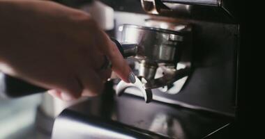 Freshly ground coffee is poured from a professional coffee grinder into a container, which is taken by a woman's hand. Close-up, no face in the frame video
