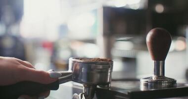 Pressing freshly ground coffee before sending it to a professional coffee machine. In the frame, female hands close up video