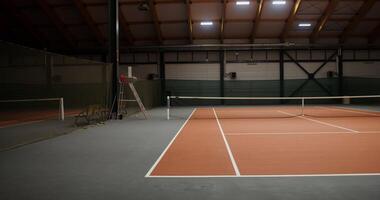 An empty tennis court with a rubberized orange covering on the floor and a net stretched in the middle, the gradually transitions from one edge of the cort to the other, no people in the video