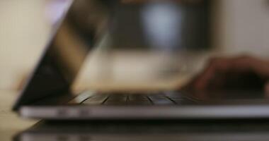 A man opens the lid of a laptop and starts typing, a very close-up, the screen is blurred, there are only hands in the frame, there is no face video