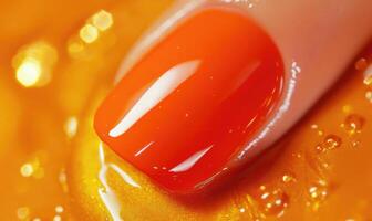 A hand with orange nails is shown on a gold colored surface photo