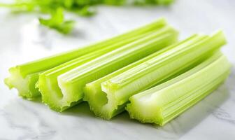 A bunch of celery sticks are on a white table photo