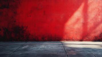 A vibrant red wall meets a stark concrete floor, shadows playing across the textures creating a study in contrast and moody atmosphere. photo