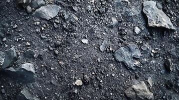A high-angle shot showcases a dense layer of rocks and gravel in varying shapes, sizes, and shades of dark gray, creating a textured surface. photo