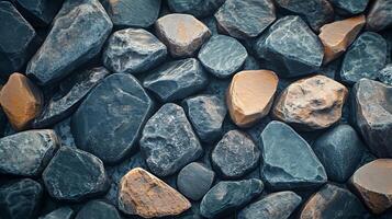 Pile of various sized, colored rocks creates an earthy background. The rock colors are varying shades of gray and brown, adding depth. photo