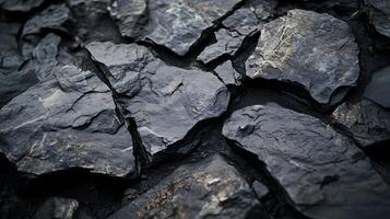 A collection of dark gray rocks with rough textures and jagged edges, tightly packed together, creating a visually striking pattern. photo