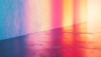 Abstract view of a textured wall bathed in colorful light transitioning from blue to yellow and red, reflected on a smooth surface. photo