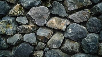 A robust wall of rough, grey stones stacked together creating a rustic and natural pattern. Geological texture on outdoor surface. photo