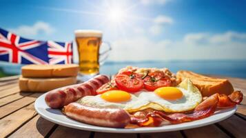 A plate of food with eggs, sausages, bacon, tomatoes, and bread on a table with a glass of beer and a Union Jack flag in the background. photo