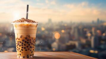 A cup of boba tea with a straw on top of a wooden table overlooking a city skyline. photo