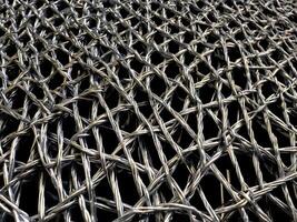 A finely focused shot of metal wire mesh, displaying a complex, repeating geometric design. photo