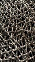 A macro shot of woven metal wire mesh, showcasing its repeating pattern. photo