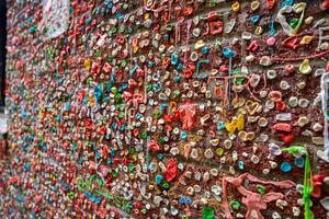 The Gum Wall in Seattle's Pike Place Market area features a brick wall covered in vibrant layers of chewed gum, creating a textured and colorful display. photo