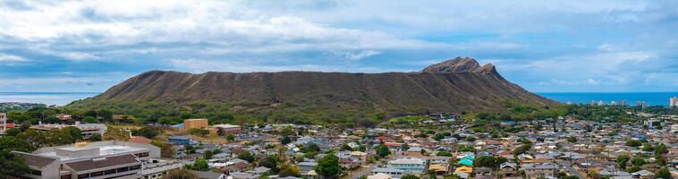 Diamond Head Crater rises above a residential area on Oahu, Hawaii, with rugged slopes, the Pacific Ocean in the background, and partly cloudy skies. photo