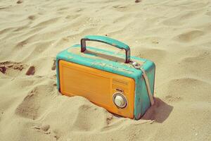 Vintage portable radio partially buried in sand on a sunlit beach in retro style photo