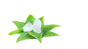 6. Piece of alum stone on green leaf against white background. This image emphasizes the connection between natural minerals and plant based ingredients in traditional practices and holistic wellness. photo