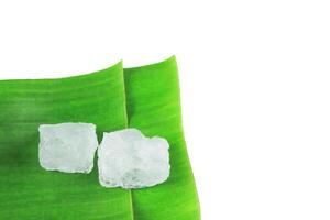 8. Pieces of alum stone on green banana leaf against white background. Concept of the connection between natural minerals and plant based ingredients in traditional practices and holistic wellness. photo