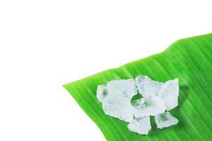4. Pieces of alum stone on green banana leaf against white background. Concept of the connection between natural minerals and plant based ingredients in traditional practices and holistic wellness. photo