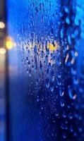 Evocative close up shot of raindrops clinging to glass surface with soft bokeh background photo