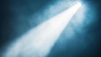 Illuminating theatrical spotlight shining on a dark blue foggy stage background photo