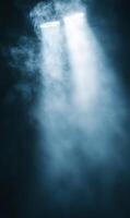 Mystical spotlights cutting through hazy atmosphere in a darkened space filling with fog photo