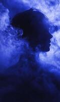 Ethereal portrait showcasing a silhouette enveloped by mystical blue fog and artistic shadows photo