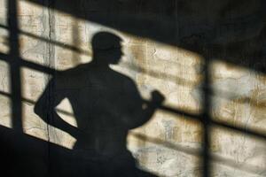 A man is running in front of a wall, casting a shadow on the wall photo