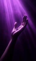 Hand reaching towards ethereal purple light, seeking inspiration or divine intervention photo