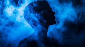 Silhouette portrait of a person engulfed in flowing blue smoke a symbol of thoughts photo