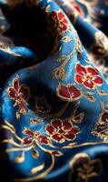 Intricate textile design featuring elegant floral patterns in gold and crimson on azure fabric photo