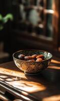 Still life of dates in patterned bowl with sunshine casting shadows on wooden surface photo