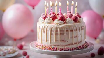 Strawberry birthday cake positioned on frame's right features white dripping glaze, lit candles, and colorful sprinkles, set against soft pastel balloon background. cake photo