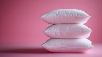 Pure white fluffy pillows stacked against soft pink background create minimalist composition with right-side positioning, emphasizing textile textures and comfort. gentle photo