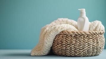 Woven wicker laundry basket displays white knitted sweater and detergent bottle, positioned rightward against soft blue backdrop in minimalist, cozy home setting. tidy photo