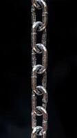 Close-up view of a shiny metallic chain hanging against a dark background. photo