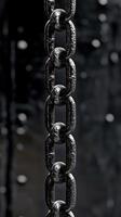 Close up of a heavy metal chain against a blurred dark background featuring water droplets. photo