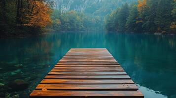 Tranquil wooden pier extending over clear blue water in a serene forest landscape. photo