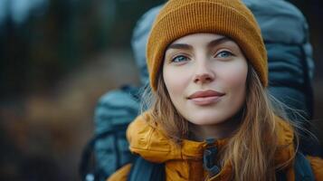Adventurer wearing a beanie poses outdoors with backpack during autumn hike in nature. photo
