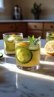 Refreshing cucumber lemonade served in glasses on a marble countertop during daytime. photo
