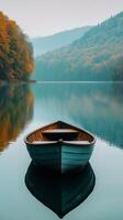 Tranquil boat floating on calm water surrounded by autumn trees in a serene mountain landscape. photo