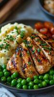 Grilled chicken served with mashed potatoes and green peas on a plate at a cozy dinner table. photo