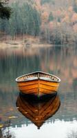 Wooden boat floating on calm lake reflecting autumn foliage at dawn. photo