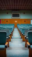 Interior of a conference hall with rows of empty seats focused on the stage area ahead. photo