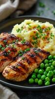 Grilled chicken breast served with creamy mashed potatoes and vibrant green peas for a healthy meal. photo
