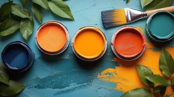 Brightly colored paint jars arranged artistically on a vibrant blue surface with green leaves and a brush. photo